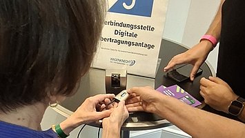 Besuchende verbinden ihr Hörsystem mit der digitalen Übertragungsanlage