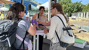 Besuchende stehen an einem Stand auf dem Berliner Platz.