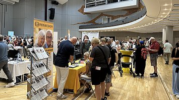 Besuchende stehen an Ständen in der Hilfsmittelausstellung im Hegelsaal